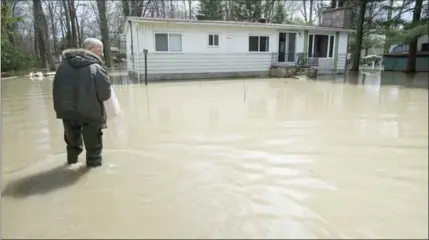  ?? PAUL CHIASSON, THE CANADIAN PRESS ?? Alain Belanger walks up to his home Tuesday in Rigaud, Que. Numerous Quebec municipali­ties are dealing with floods after heavy rains.