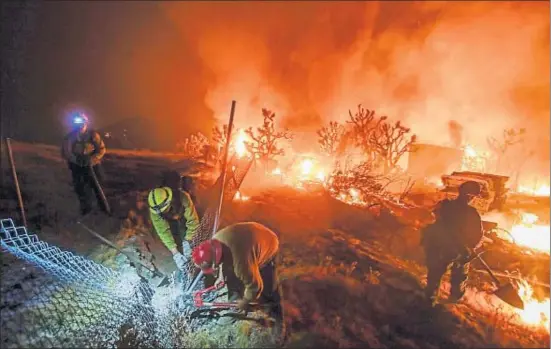  ?? RINGO CHIU / AFP ?? Unos bomberos abriéndose paso, la noche del martes, cerca del lugar donde se inició el fuego, en Cajon Pass