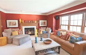  ??  ?? The family room, painted a vivid red, features a gas fireplace and colorful throw pillows.