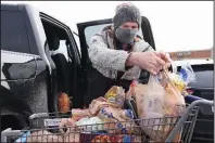  ?? (Arkansas Democrat-Gazette/Staci Vandagriff) ?? Brad Lawson loads groceries into his truck Saturday at the Kroger store on Chenal Parkway in Little Rock. Lawson said his family bought more groceries than usual to prepare for the winter weather.