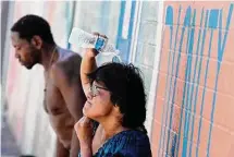  ?? Matt York/Associated Press ?? People who are homeless cool down with water in downtown Phoenix, which marked its 15th day of 110-degree weather Friday.