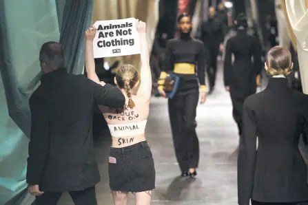  ?? — AFP photos ?? A security guard runs to stop a woman holding a poster reading ‘animals are not clothing’ during the Fendi collection show at the Milan Fashion Week Womenswear Autumn/Winter 2024-2025 in Milan.