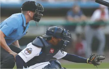  ?? JULIO CORTEZ / THE ASSOCIATED PRESS ?? Umpire Brian deBrauwere huddles behind catcher James Skelton of the York Revolution during Atlantic
League All-Star Game. His earpiece is connected to an automated pitch-calling system.