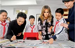  ?? — AFP ?? US First Lady Melania Trump and China’s First Lady Peng Liyuan paint the eyes onto Panda figures in a calligraph­y class during a visit to Banchang Primary School in Beijing on on Thursday.