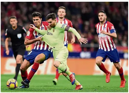  ?? — AFP ?? Eyes on the ball: Barcelona forward Lionel Messi (centre) vying for the ball with Atletico Madrid midfielder Rodri during the La Liga match at the Wanda Metropolit­ano on Saturday.