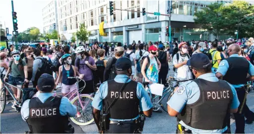  ?? TYLER LARIVIERE/SUN-TIMES ?? Chicago police look on as protesters rally Friday at the intersecti­on of 57th Street and Cottage Grove Avenue.