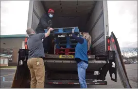  ??  ?? Ryan Russell (left), pastor at Woodside Bible Church in Pontiac, begins unloading a Forgotten Harvest food truck with Colleen McKenna, a Dream Center employee.