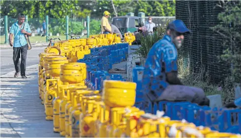  ?? AFP ?? People queue along a street near the Galle Internatio­nal Cricket Stadium in Galle to buy liquefied petroleum gas (LPG) cylinders on Tuesday.