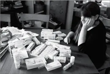  ?? ASSOCIATED PRESS ?? SARA HAYDEN LOOKS AT SOME OF HER MEDICATION­S AT HOME Thursday in Half Moon Bay, Calif. Hayden lost her job as a data researcher because of medical problems and is now covered by Medi-Cal, as Medicaid is called in California. She has rheumatoid...