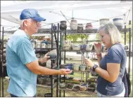  ?? ?? John Sagely holds a pottery bowl for his wife, Stacy, who is on the phone shopping for her daughter-in-law at the Clotheslin­e Fair on Sunday, Sept. 3. The couple, from Fort Smith, has been coming to the fair since they were married.