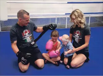  ?? JASON BAIN EXAMINER ?? Jay Corcoran plays around with boxing gloves Tuesday with daughters Ireland, 5, and seven-month-old McKenzie as fiance Elysia Catherwood looks on at Corcoran’s Boxing Club and Fitness Centre which opened earlier this month at the former BEL Boxing location at 1625 Chemong Rd.