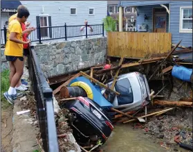  ?? AP Photo/David McFadden ?? Damage: Residents gather by a bridge to look at cars left crumpled in one of the tributarie­s of the Patapsco River that burst its banks as it channeled through historic Main Street in Ellicott City, Md., Monday. Sunday's destructiv­e flooding left the...