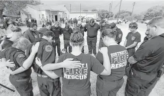  ?? Eric Gay / Associated Press ?? First responders join in prayer following a Veterans Day event near the Sutherland Springs First Baptist Church, one of many American communitie­s observing the holiday. Story on page A27.