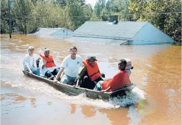  ?? ALAN MARLER/AP 1999 ?? A boat with residents of Princevill­e, N.C., travels down Main Street after the Tar River flooded the town.