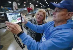  ?? JOHN MINCHILLO — THE ASSOCIATED PRESS ?? In this Friday photo, Deane Sager of Louisville, right, and his wife, Cathy, use a Histopad tablet to view scenes from operations on the western front of World War II at the The National Museum of the U.S. Air Force in Dayton, Ohio. French-developed technology making its U.S. debut this month will allow new views of the D-Day invasion 75years ago that began the liberation of France and helped end World War II.