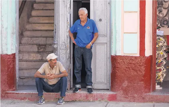  ?? MIAMI HERALD/TNS ?? Two men watch tourists on Feb. 15, 2017, in Havana, Cuba.