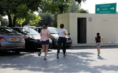  ?? (Amir Cohen/Reuters) ?? PEOPLE RUN for shelter as a siren sounds yesterday during a rocket attack near Yad Mordechai.