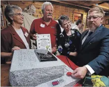  ?? CLIFFORD SKARSTEDT EXAMINER ?? Family members Norma Sedgwick, left, John Sedgwick and Wendy Sedgwick look on as Mark Nielsen places a poppy on Saturday.