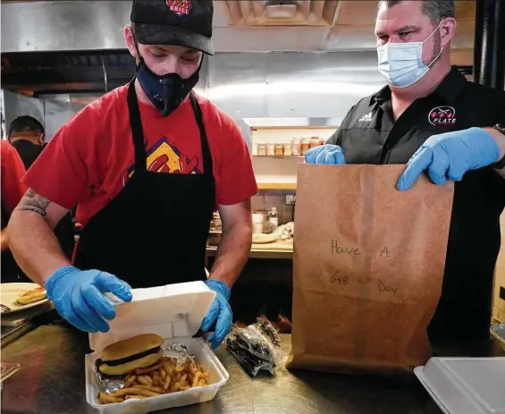  ?? Melissa Phillip / Staff photograph­er ?? Sean Kennedy, left, Jax Grill general manager, and Paul Miller, right, owner of Gr8 Plate Hospitalit­y, have seen a 10 to 15 percent spike in plastic bags and utensils.