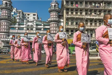  ?? Hkun Lat / Getty Images ?? Buddhist monks hold images of ousted leader Aung San Suu Kyi during a protest rally in Yangon.