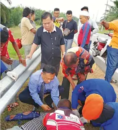  ??  ?? Dr Teo comes to the aid of a seriously injured motorcycli­st in Rantau after handing out food coupons to 300 students from five schools in Negri Sembilan.