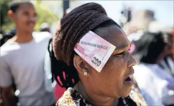  ??  ?? A woman wears a fake R200 note in her headdress with the words “National Minimum Wage’’ printed on it during a Cosatu protest.