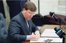  ?? Rogelio V. Solis / Associated Press ?? Mississipp­i Gov. Tate Reeves signs the first state bill in the U.S. this year to ban transgende­r athletes from competing on female sports teams at the Capitol in Jackson, Miss., on March 11. The NCAA has reached a delicate moment: It must decide whether to punish states that have passed laws limiting the participat­ion of transgende­r athletes by barring them from hosting its softball and baseball tournament­s.