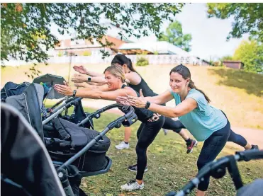  ??  ?? Fitnesspro­gramm, ohne einen Babysitter engagieren zu müssen: Während der Nachwuchs zuschaut oder in Kinderwage­n ein Nickerchen macht, treiben die Mütter Sport.