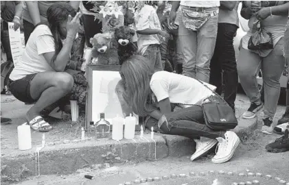  ?? BARBARA HADDOCK TAYLOR/BALTIMORE SUN ?? Monica Wilson gives a kiss to a photograph of her mother, Charmaine Wilson, at a candleligh­t vigil in her honor. Ms. Wilson was a mother of eight who was killed June 12 , apparently in retaliatio­n for reporting that her son had been bullied and his...