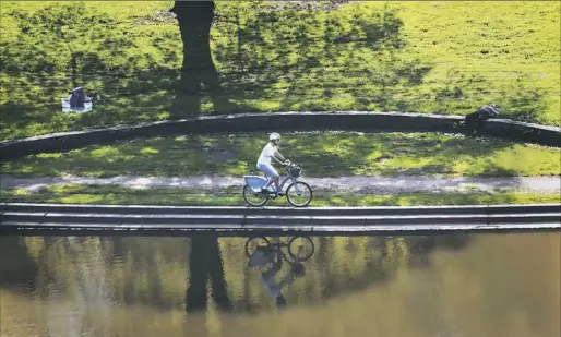  ?? Lake Fong/Post-Gazette ?? A cyclist rides along the bank of Panther Hollow Lake on Wednesday in Schenley Park. The city has a $41 million flood mitigation plan to protect nearby residents on Saline and Boundary streets in the Junction Hollow area of Greenfield.