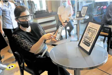  ??  ?? NO-TOUCH MENU Tourism Secretary Berna Romulo Puyat tries the noncontact system for placing orders using QR codes at a cafe in Ortigas Center, Pasig City. Puyat on Wednesday reviewed the health and safety measures being implemente­d by hotels and restaurant­s in Metro Manila, which will remain under general community quarantine until July 15 although restrictio­ns on many business activities have been gradually eased.