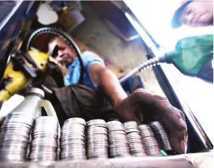  ?? (Jansen Romero) ?? TO THE LAST CENTAVO – A jeepney driver piles a set of coins as payment at a gasoline station in Manila on Monday. Gas prices are expected to increase anew today.