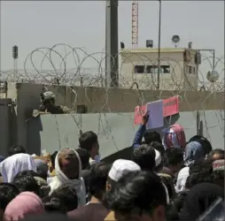  ?? Wali Sabawoon/Associated Press ?? U.S. soldiers stand inside the airport as hundreds of people gather near an evacuation control checkpoint on the perimeter of the Hamid Karzai Internatio­nal Airport in Kabul, Afghanista­n, on Thursday.