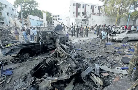 ?? FARAH ABDI WARSAMEH/THE ASSOCIATED PRESS ?? Rescue workers stand near the wreckage of vehicles in Mogadishu, Somalia, on Sunday, after a car bomb was detonated Saturday night. A Somali police officer said security forces ended a night-long siege at a Mogadishu hotel by attackers who stormed the...