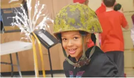  ?? BRENDAN AHERN/THE NEWS ?? New Glasgow Academy Grade 3 student Kylie Dunn tries on a Canadian Armed Forces combat helmet on display, one of many artifacts for the school's Remembranc­e Day event.
