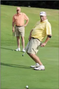  ??  ?? BODY ENGLISH: Steve Baldwin, right, reacts to sinking a putt as his namesake looks on during the Fellowship of Christian Athletes golf tournament Saturday at Magellan course in Hot Springs Village.