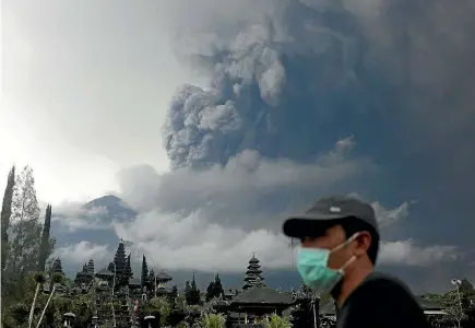  ?? PHOTO: REUTERS ?? Mt Agung volcano erupts as seen from Besakih Temple in Karangasem, Bali. The authoritie­s have been distributi­ng masks for local residents, and have ordered people within a widened 10km exclusion zone to evacuate the area. The main resorts of Kuta and...