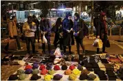  ?? EBRAHIM NOROOZI / AP ?? Pedestrian­s look over a vendor’s offerings in downtown Tehran on Monday. Iran greeted the re-imposition of U.S. sanctions on Monday with air defense drills and a statement from President Hassan Rouhani that the nation faces a “war situation.”