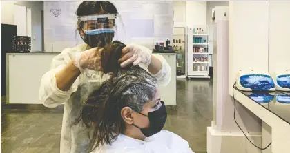  ?? RANIA SANJAR/AFP VIA GETTY IMAGES ?? A hairdresse­r clad in face shield and mask dyes a client’s hair at a women’s salon in Saudi Arabia’s capital Riyadh as the country begins to reopen following the lifting of a lockdown during the COVID-19 pandemic.