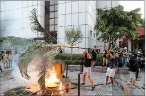  ?? AP/KIN CHEUNG ?? Pro-democracy demonstrat­ors in Hong Kong use palm fronds and other items to set a fire Sunday during protests outside a mall.