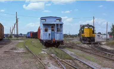  ?? Two photos, Brian Buchanan ?? While the Chicago & North Western crew stays in the clear, a Chicago Metra commuter railroad crew delivers empty ballast cars for loading on Wisconsin Central. At left, a WC train waits to cross B-12 and head to a Chicago connection.