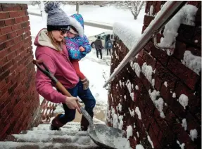  ?? TED SCHURTER / THE STATE JOURNAL-REGISTER ?? Morgan Miller carries her 1-year-old daughter, Mia Jennings, in one arm as she shovels the stairs to her Springfiel­d, Illinois, home with the other Sunday.