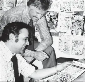  ?? The Associated Press ?? In this 1976 file photo, Stan Lee, standing, publisher of Marvel Comics, discusses a "Spiderman" comic book cover with artist John Romita at Marvel headquarte­rs in NewYork.