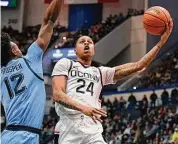  ?? Jessica Hill/Associated Press ?? UConn’s Jordan Hawkins (24) shoots around Marquette’s Olivier-Maxence Prosper (12) on Tuesday night.