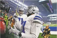  ?? RON JENKINS ASSOCIATED PRESS ?? Cowboys running back Ezekiel Elliott, front, pulls out a $20 bill to put in the Salvation Army kettle after scoring a touchdown against the Redskins during Thursday’s game in Arlington, Texas.