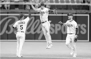  ?? CHRIS O’MEARA/AP ?? Rays left fielder Brett Phillips, center, celebrates with shortstop Wander Franco, left, and center fielder Kevin Kiermaier after they defeated the Mariners on Thursday.