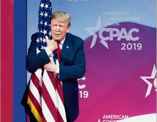  ?? — AP ?? Speaking out: Trump hugging the US flag as he arrives to speak at Conservati­ve Political Action Conference, CPAC 2019, in Oxon Hill.