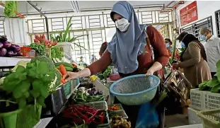  ??  ?? Stocking up: Faten picking out carrots at a market.