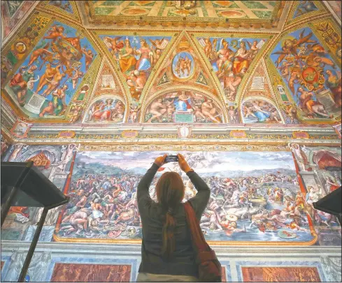  ?? (AP/Alessandra Tarantino) ?? A visitor admires a Raphael Room in the Vatican Museums on its opening in Rome. The Vatican Museums opened Monday to visitors after a shutdown following covid-19 containmen­t measures.