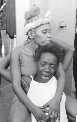  ?? AP PHOTOS ?? The relative (front) of a person found dead in the street reacts after an overnight shooting in the Petion Ville neighbourh­ood of Port-au-Prince, Haiti, yesterday.